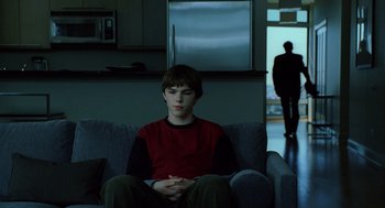 Movie still from “The Weather Man” (2005), directed by Gore Verbinski – A boy sitting on a couch in a living room; Wide shot, Over the shoulder angle
