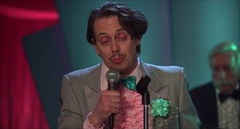 Movie still from “The Wedding Singer” (1998), directed by Frank Coraci – A man in a suit holding a microphone and wearing a green bow tie; Close Up shot, Low angle