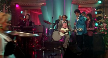 Movie still from “The Wedding Singer” (1998), directed by Frank Coraci – A group of men in suits and ties playing instruments; Wide shot, Low angle