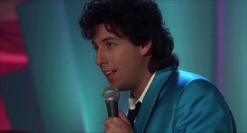 Movie still from “The Wedding Singer” (1998), directed by Frank Coraci – A man in a blue jacket holding a microphone; Close Up shot, Over the shoulder angle
