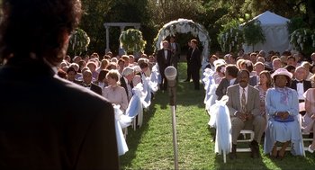 Movie still from “The Wedding Singer” (1998), directed by Frank Coraci – A group of people sitting in a field with a microphone; Wide shot, High angle