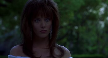 Movie still from “The Wedding Singer” (1998), directed by Frank Coraci – A beautiful woman with long brown hair and blue eyes looking at the camera; Close Up shot, Over the shoulder angle