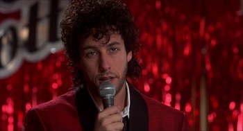 Movie still from “The Wedding Singer” (1998), directed by Frank Coraci – A man with curly hair is holding a microphone in his hand; Close Up shot, Low angle