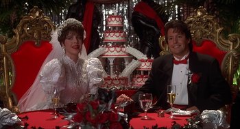 Movie still from “The Wedding Singer” (1998), directed by Frank Coraci – A man and a woman sitting at a table with a wedding cake; Medium shot, Low angle