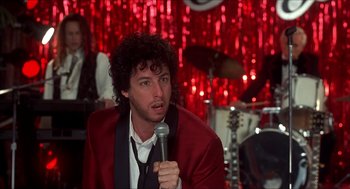 Movie still from “The Wedding Singer” (1998), directed by Frank Coraci – A man in a red jacket holding a microphone; Close Up shot, Over the shoulder angle