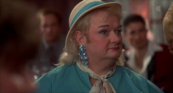 Movie still from “The Wedding Singer” (1998), directed by Frank Coraci – An older woman wearing a hat and a blue dress; Close Up shot, Over the shoulder angle