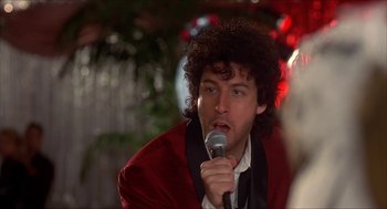 Movie still from “The Wedding Singer” (1998), directed by Frank Coraci – A man in a red jacket is holding a microphone; Close Up shot, Over the shoulder angle