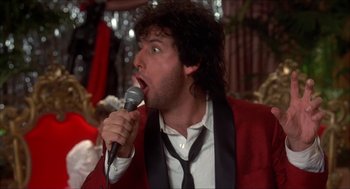 Movie still from “The Wedding Singer” (1998), directed by Frank Coraci – A man in a red jacket is singing into a microphone; Close Up shot, Low angle