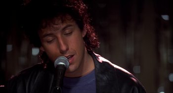 Movie still from “The Wedding Singer” (1998), directed by Frank Coraci – A man with curly red hair is singing into a microphone; Close Up shot, Low angle