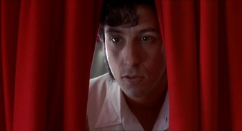 Movie still from “The Wedding Singer” (1998), directed by Frank Coraci – A man looking through a red curtain at the camera; Close Up shot, Low angle