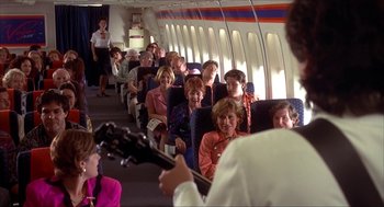 Movie still from “The Wedding Singer” (1998), directed by Frank Coraci – A group of people sitting in a row on an airplane; Wide shot, High angle