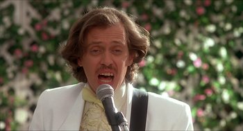 Movie still from “The Wedding Singer” (1998), directed by Frank Coraci – A man in a white suit is singing into a microphone; Close Up shot, Low angle