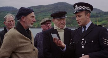 Movie still from “The Wicker Man” (1973), directed by Robin Hardy – A group of men standing next to a body of water; Medium shot, Over the shoulder angle