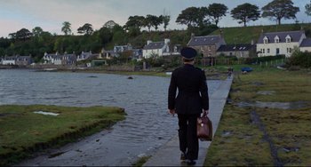 Movie still from “The Wicker Man” (1973), directed by Robin Hardy – A man in a uniform walking down a sidewalk; Extreme Wide shot, High angle
