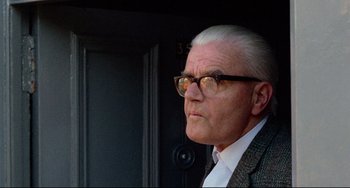 Movie still from “The Wicker Man” (1973), directed by Robin Hardy – An older man wearing glasses and a suit; Close Up shot, Low angle