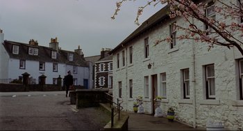 Movie still from “The Wicker Man” (1973), directed by Robin Hardy – A person walking down a street near a building; Extreme Wide shot, High angle
