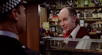 Movie still from “The Wicker Man” (1973), directed by Robin Hardy – A man with a bald head in a store; Close Up shot, Over the shoulder angle