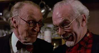 Movie still from “The Wicker Man” (1973), directed by Robin Hardy – Two older men wearing glasses and a red shirt; Close Up shot, Low angle