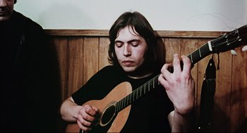 Movie still from “The Wicker Man” (1973), directed by Robin Hardy – A man sitting in front of an acoustic guitar; Close Up shot, Low angle