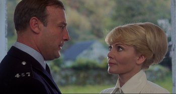 Movie still from “The Wicker Man” (1973), directed by Robin Hardy – A man and a woman looking at each other in front of trees; Close Up shot, Low angle