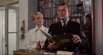 Movie still from “The Wicker Man” (1973), directed by Robin Hardy – A man and a woman are looking at a book; Medium shot, Low angle