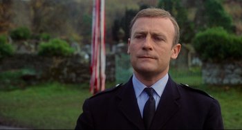 Movie still from “The Wicker Man” (1973), directed by Robin Hardy – A person wearing a suit and tie; Close Up shot, Low angle