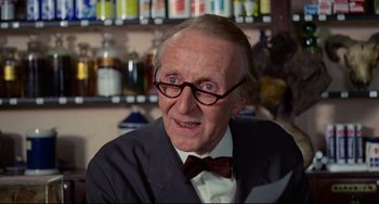 Movie still from “The Wicker Man” (1973), directed by Robin Hardy – An older man wearing a suit and bow tie; Close Up shot, Over the shoulder angle