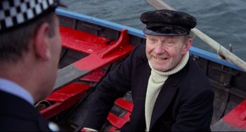Movie still from “The Wicker Man” (1973), directed by Robin Hardy – An older man sitting in a boat on the water; Close Up shot, High angle