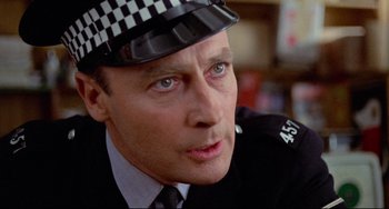 Movie still from “The Wicker Man” (1973), directed by Robin Hardy – A man in a police officer's uniform looking at the camera; Close Up shot, Over the shoulder angle