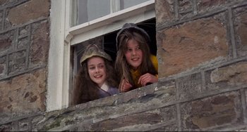Movie still from “The Wicker Man” (1973), directed by Robin Hardy – Two young girls looking out of a window; Medium shot, Low angle