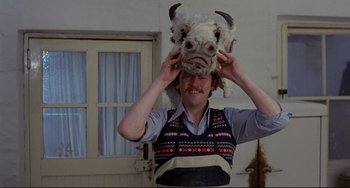 Movie still from “The Wicker Man” (1973), directed by Robin Hardy – A man in a sweater holding up an animal head; Medium shot, Low angle