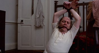 Movie still from “The Wicker Man” (1973), directed by Robin Hardy – A man with his hands tied up with a rope around his neck; Medium shot, High angle