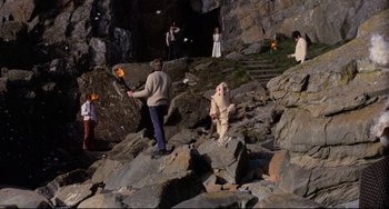 Movie still from “The Wicker Man” (1973), directed by Robin Hardy – A group of people standing on a rocky cliff holding torches; Extreme Wide shot, High angle