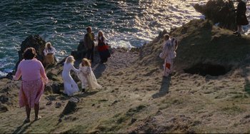 Movie still from “The Wicker Man” (1973), directed by Robin Hardy – A group of people standing on top of a beach; Extreme Wide shot, High angle