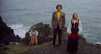 Movie still from “The Wicker Man” (1973), directed by Robin Hardy – A group of people standing on top of a cliff near the ocean; Wide shot, Low angle