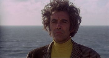 Movie still from “The Wicker Man” (1973), directed by Robin Hardy – A man in a yellow shirt and a plaid jacket looks into the camera; Close Up shot, Low angle