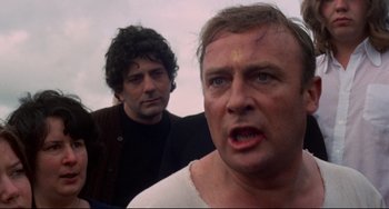 Movie still from “The Wicker Man” (1973), directed by Robin Hardy – Two men standing next to each other on a beach; Close Up shot, Over the shoulder angle