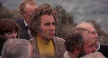 Movie still from “The Wicker Man” (1973), directed by Robin Hardy – A man in a yellow sweater and a jacket; Close Up shot, Over the shoulder angle