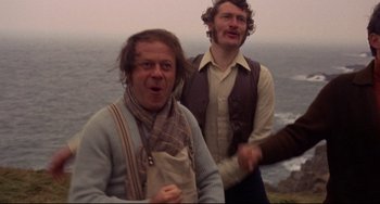 Movie still from “The Wicker Man” (1973), directed by Robin Hardy – Two men standing next to each other near the ocean; Medium shot, Low angle