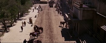 Movie still from “The Wild Bunch” (1969), directed by Sam Peckinpah – A group of people riding horses down a street; Extreme Wide shot, High angle