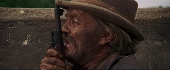 Movie still from “The Wild Bunch” (1969), directed by Sam Peckinpah – An old man with a beard holding a gun; Close Up shot, Over the shoulder angle
