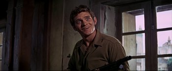 Movie still from “The Wild Bunch” (1969), directed by Sam Peckinpah – A man with a gun in his hand and smiling; Close Up shot, Low angle