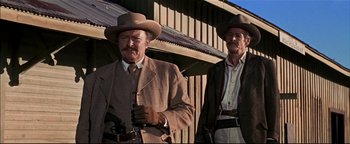 Movie still from “The Wild Bunch” (1969), directed by Sam Peckinpah – Two men standing next to each other holding guns; Medium shot, Low angle