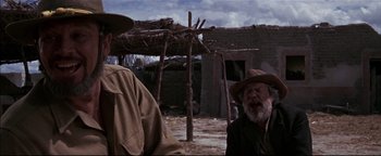 Movie still from “The Wild Bunch” (1969), directed by Sam Peckinpah – Two men standing in front of an adobe building; Medium shot, Over the shoulder angle