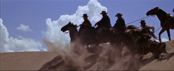 Movie still from “The Wild Bunch” (1969), directed by Sam Peckinpah – A group of men riding horses through the desert; Wide shot, Low angle