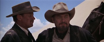 Movie still from “The Wild Bunch” (1969), directed by Sam Peckinpah – A man in a cowboy hat standing next to another man; Close Up shot, Low angle