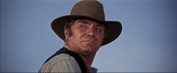 Movie still from “The Wild Bunch” (1969), directed by Sam Peckinpah – An older man wearing a brown hat and a striped shirt; Close Up shot, Low angle