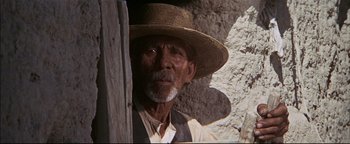 Movie still from “The Wild Bunch” (1969), directed by Sam Peckinpah – An old man wearing a straw hat looking out of a window; Close Up shot, Low angle