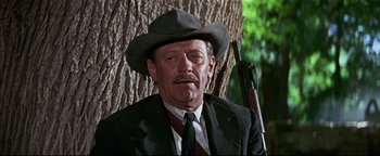 Movie still from “The Wild Bunch” (1969), directed by Sam Peckinpah – A man in a suit and a hat with a rifle; Close Up shot, Low angle