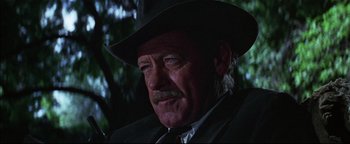 Movie still from “The Wild Bunch” (1969), directed by Sam Peckinpah – An older man wearing a cowboy hat and a suit; Close Up shot, Over the shoulder angle